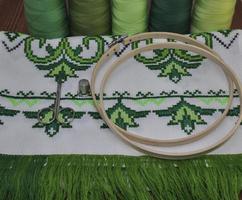 cadre de broderie au point de croix serviette en bois en fil vert vif sur fond de table en bois photo