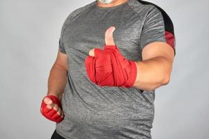 les mains du sportif enveloppées dans un bandage de sport élastique rouge montrent un signe similaire photo