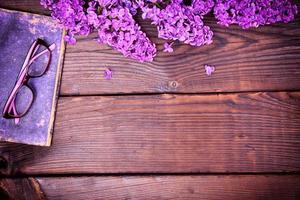 branche d'un lilas violet et d'un vieux livre avec des lunettes photo