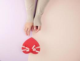 deux mains tiennent une boîte rouge fermée en papier en forme de coeur photo