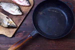 trois carpes fraîches, à côté d'une poêle en fonte noire photo