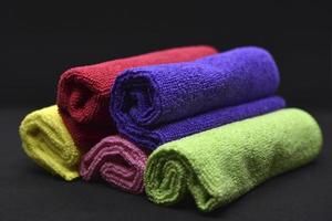 serviettes multicolores sur fond noir. serviettes éponge. chiffons colorés en rouleaux. chiffons enroulés. photo
