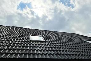 fenêtre de toit ouverte de style velux avec des tuiles noires environnantes photo