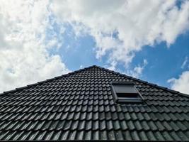 fenêtre de toit ouverte de style velux avec des tuiles noires environnantes photo