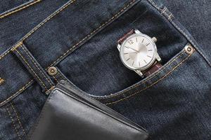 montre-bracelet et porte-monnaie sur la poche de jeans en denim photo