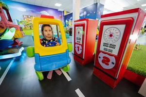 jouer à l'aire de jeux intérieure du centre de jeux, fille dans la station-service de voiture jouet. photo