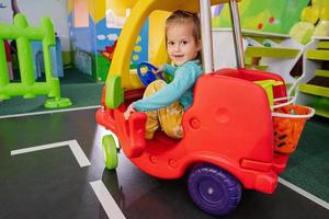 enfants jouant à l'aire de jeux intérieure du centre de jeux, fille dans une petite voiture. photo