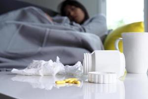 se concentrer sur les médicaments qui sont sur la table. à l'arrière, il y avait une femme souffrant de fièvre allongée sur le canapé. photo