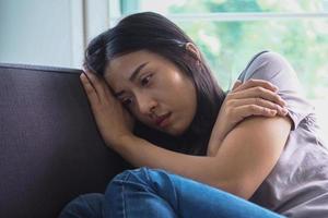 une fille triste assise sur le canapé inquiète et inquiète. photo