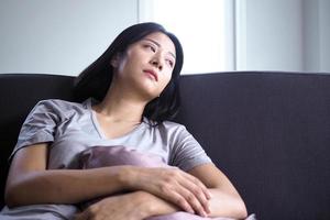 femmes asiatiques assises sur le canapé. les femmes sont confuses, déçues, tristes et tristes. photo