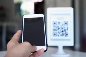 les mains utilisent le téléphone pour scanner les codes qr afin de recevoir des réductions sur les achats. photo