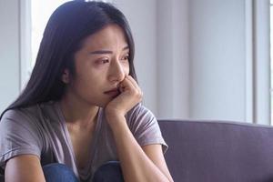 fille asiatique assise seule dans la maison. notion de dépression photo