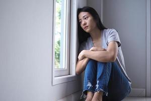 fille asiatique assise seule dans la maison. notion de dépression photo