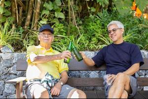 père et fils assis sur des chaises et buvant de la bière en vacances. photo