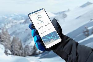 application de suivi de randonnée sur téléphone intelligent dans la main de l'homme avec gant. montagne couverte de neige en arrière-plan photo