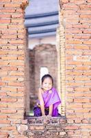 Petite fille asiatique en robe de période thaïlandaise debout dans des vestiges antiques photo