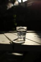 de l'eau claire dans un verre clair par contre. une alimentation saine et une eau naturelle respectueuse de l'environnement. un verre d'eau sur une table en bois. photo