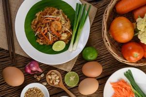 Pad thai crevettes dans un bol avec œufs, oignon nouveau et assaisonnements photo