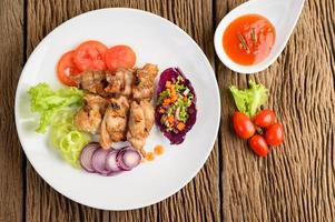 Poulet grillé sur une planche à découper en bois avec salade photo