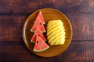 Tranches de pastèque et d'ananas sur une table en bois sombre photo