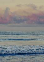 vagues de l'océan s'écraser sur le rivage pendant le coucher du soleil photo