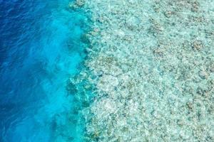 magnifique récif corallien sur l'île des maldives, paysage aérien, eau de mer peu profonde comme lagon. texture naturelle étonnante sous l'eau et à la surface de l'océan. photo