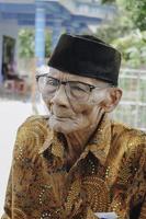 un portrait d'un vieil homme asiatique portant une chemise et des lunettes de batik photo