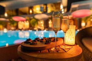 décoration romantique table à dîner aux chandelles pour la fête avec des plats spéciaux au champagne et lumière floue de la piscine et de la maison. fête de luxe ou événement de vacances photo