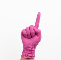 main féminine dans un gant en latex rose sur fond blanc photo