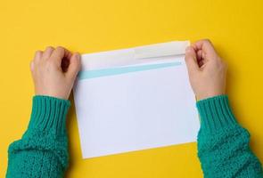 la main féminine tient des enveloppes en papier blanc sur fond orange, vue de dessus. envoi et réception de correspondance photo