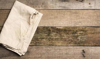 serviette en lin beige pliée sur une table faite de vieilles planches de bois gris, vue de dessus photo