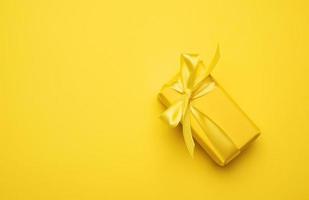 boîte rectangulaire jaune avec un cadeau emballé dans du papier jaune photo