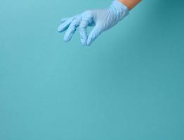 la main du médecin dans un gant médical bleu tient un objet sur un fond bleu photo