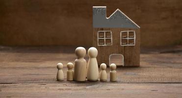 figurines familiales en bois, maison modèle sur fond marron. achat immobilier, concept de location. emménager dans de nouveaux appartements photo