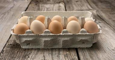 oeufs bruns entiers frais dans un emballage en papier sur un fond de bois gris photo