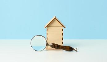 loupe et maison en bois sur fond bleu. concept de location, d'achat et de vente de biens immobiliers. services d'agent immobilier, réparation et entretien de bâtiments photo