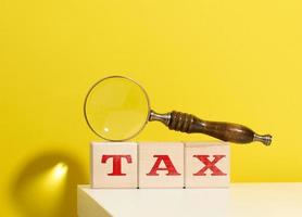 cubes en bois avec la taxe d'inscription et une loupe brune sur fond jaune photo