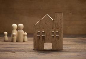 figurines familiales en bois, maison modèle sur fond marron. achat immobilier, concept de location photo