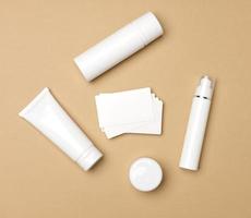 pot, bouteille et tubes en plastique blanc vides pour cosmétiques sur fond beige. emballage pour crème, gel, sérum, publicité et promotion de produits, maquette, vue de dessus photo