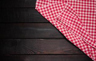 serviette de cuisine en coton rouge et blanc pliée sur fond marron en bois, vue de dessus, espace de copie photo