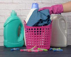 la main dans un gant rose met les choses dans un panier à linge en plastique photo