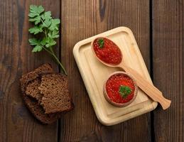 le caviar rouge de saumon rose se trouve dans une cuillère en bois sur une planche à découper. table en bois marron photo