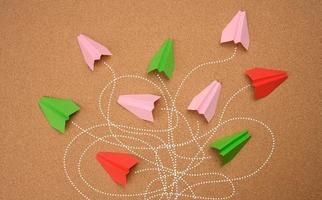 groupe d'avions en papier multicolores avec de longs chemins emmêlés sur fond marron. photo