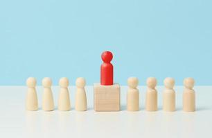 petits hommes en bois sur une table blanche, le rouge se dresse sur un cube en bois. recherche d'employés talentueux, rassemblement, manipulation des masses, sélection d'employés pour l'équipe photo