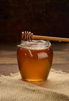 miel frais dans un bocal en verre transparent et une cuillère en bois sur une table marron photo