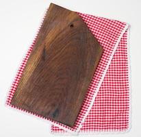planche à découper de cuisine en bois rectangulaire vide et serviette rouge dans une cage blanche sur une table blanche, vue de dessus photo
