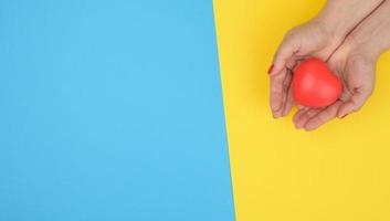 les mains féminines tiennent un coeur rouge, fond bleu. concept d'amour et de don photo