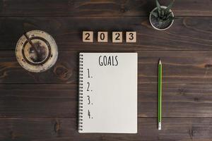 Texte des objectifs 2023 sur le bloc-notes avec une tasse de café et un stylo sur un bureau en bois photo