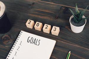 Texte des objectifs 2023 sur le bloc-notes avec une tasse de café et un stylo sur un bureau en bois photo