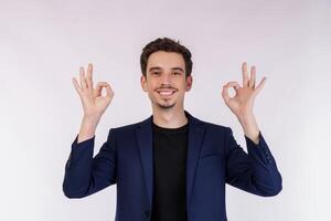 portrait d'un jeune homme d'affaires heureux et beau faisant signe ok avec la main et les doigts sur fond blanc photo